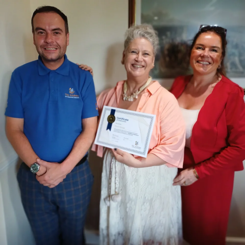 Dawn smiling with her training certificate and two people beside her